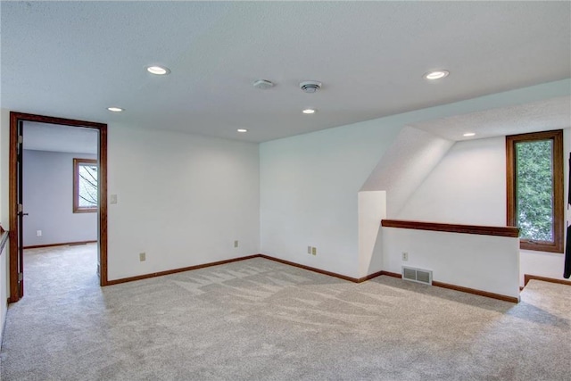 additional living space featuring light colored carpet and a textured ceiling