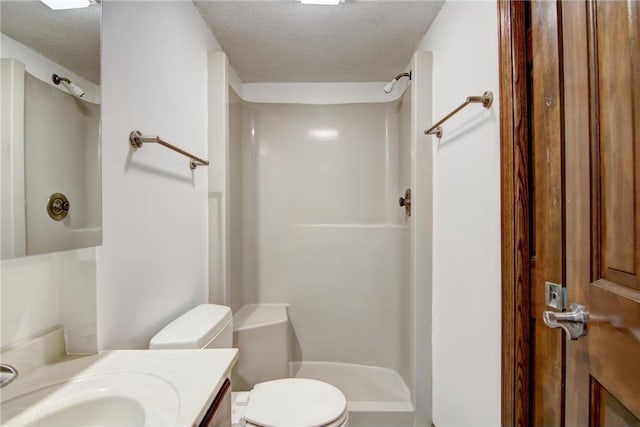 bathroom featuring a shower, vanity, toilet, and a textured ceiling