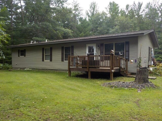 back of property with a wooden deck and a lawn