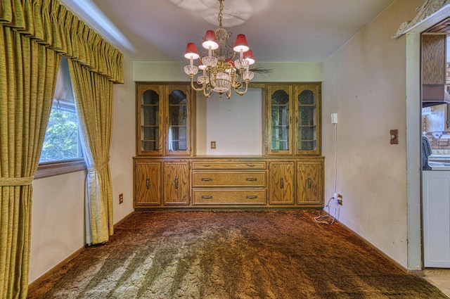 unfurnished dining area with dark colored carpet and a chandelier