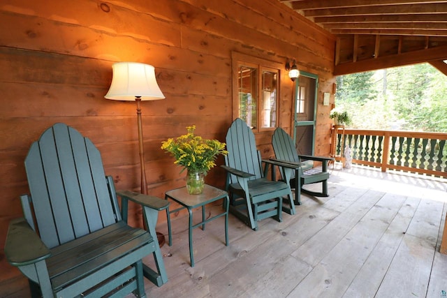 sitting room with lofted ceiling, hardwood / wood-style floors, and wooden walls