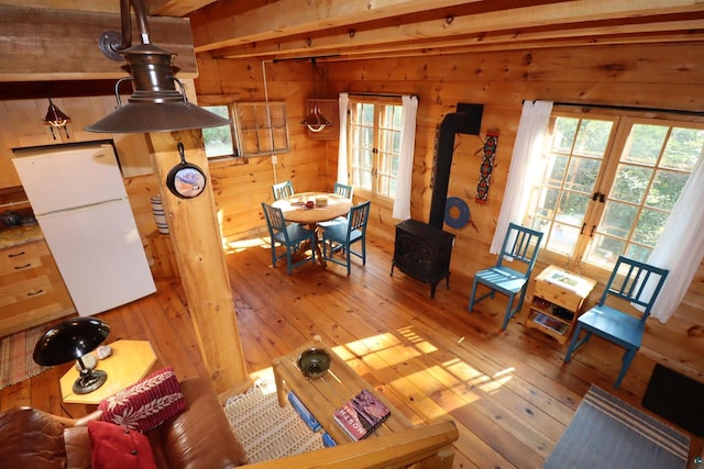 living room with light wood-type flooring, french doors, wood walls, and a wood stove