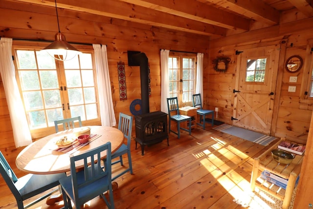 dining room featuring wood-type flooring, wooden walls, beam ceiling, and french doors