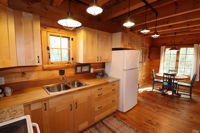 kitchen featuring a wealth of natural light, hardwood / wood-style flooring, decorative light fixtures, and white fridge