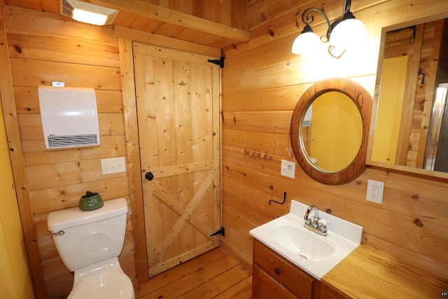 bathroom featuring toilet, wooden walls, hardwood / wood-style flooring, and vanity