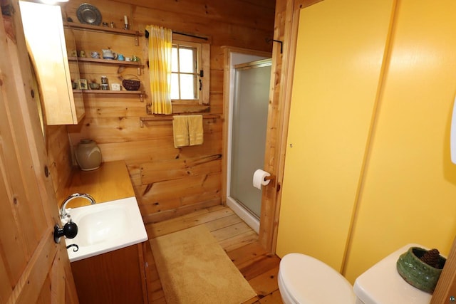 bathroom featuring vanity, toilet, wood-type flooring, and a shower with door