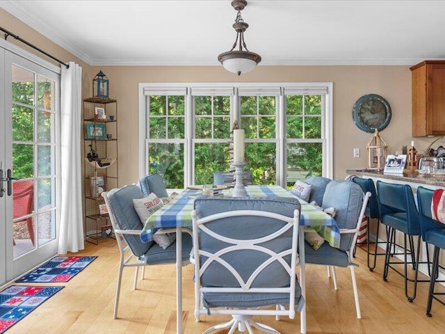 dining area featuring plenty of natural light, ornamental molding, and light hardwood / wood-style flooring