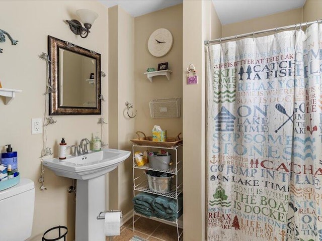 bathroom featuring toilet, a shower with curtain, and tile patterned floors