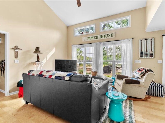 living room featuring a healthy amount of sunlight, ceiling fan, light wood-type flooring, and high vaulted ceiling