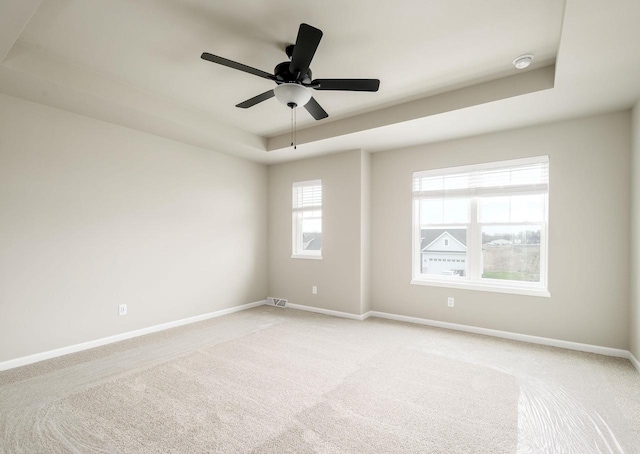 unfurnished room with light carpet, a tray ceiling, and ceiling fan