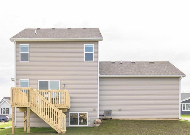 rear view of property featuring central air condition unit, a deck, and a lawn