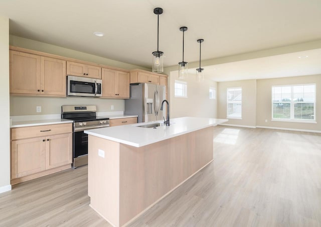 kitchen with decorative light fixtures, stainless steel appliances, light hardwood / wood-style floors, and an island with sink