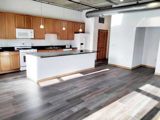 kitchen featuring a high ceiling, hanging light fixtures, sink, white appliances, and dark hardwood / wood-style flooring