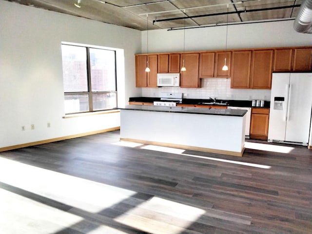 kitchen featuring tasteful backsplash, dark hardwood / wood-style flooring, pendant lighting, sink, and white appliances