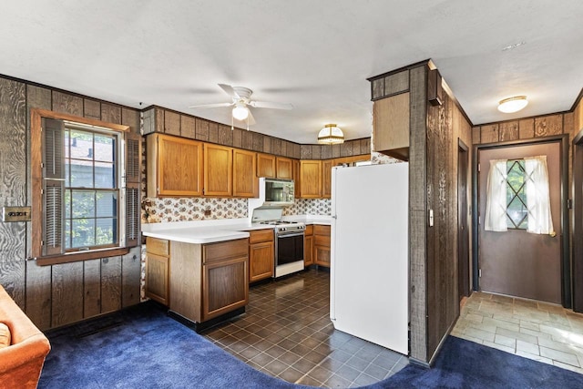 kitchen featuring decorative backsplash, white appliances, ceiling fan, and wooden walls