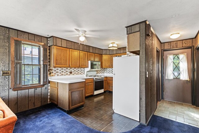 W11585 Demynck Rd, Lodi, WI 53555 - kitchen with light countertops, dark carpet, brown cabinetry, wood walls, and white appliances