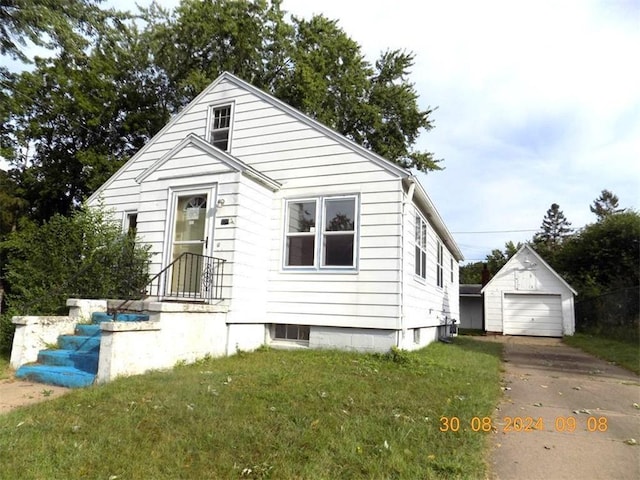 bungalow with a garage, an outbuilding, concrete driveway, and a front lawn