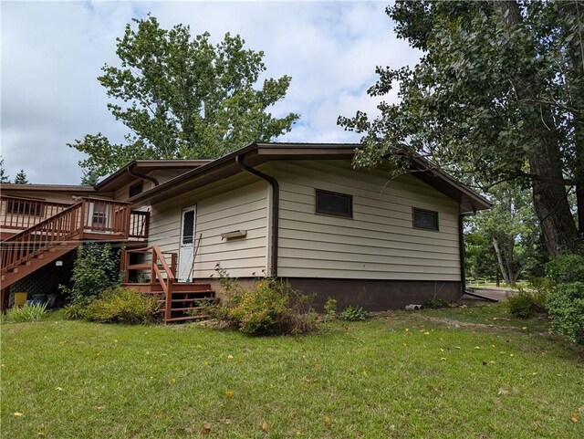 exterior space featuring a wooden deck and a lawn