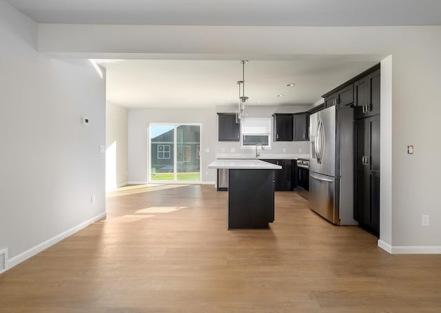 kitchen featuring light hardwood / wood-style flooring, stainless steel appliances, a center island, and hanging light fixtures