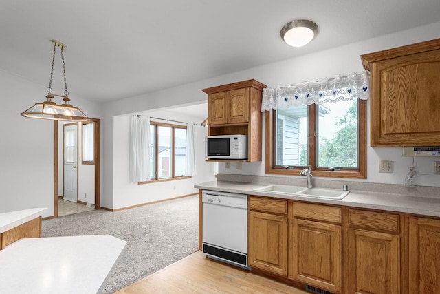 kitchen with white appliances, plenty of natural light, light carpet, and sink