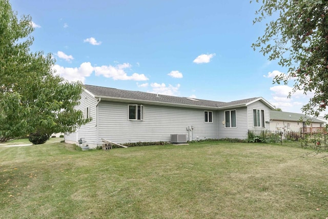 back of house featuring central air condition unit and a lawn