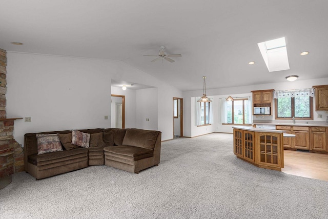 living room featuring light colored carpet, lofted ceiling with skylight, and ceiling fan