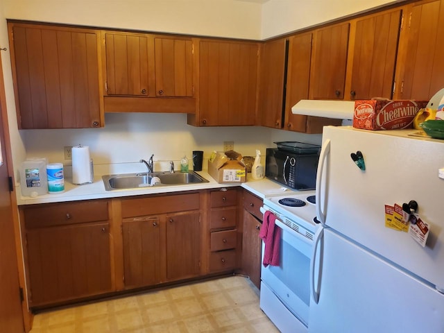 kitchen with light floors, light countertops, a sink, white appliances, and under cabinet range hood