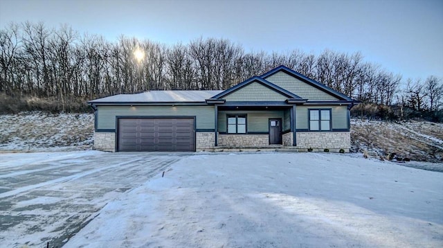 view of front facade featuring stone siding, an attached garage, and driveway