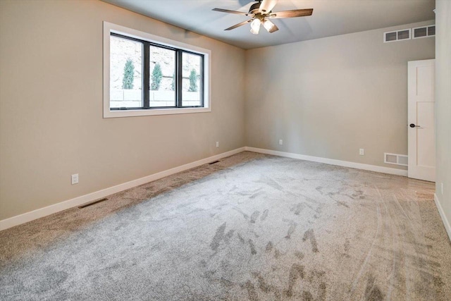 carpeted spare room with baseboards, visible vents, and ceiling fan