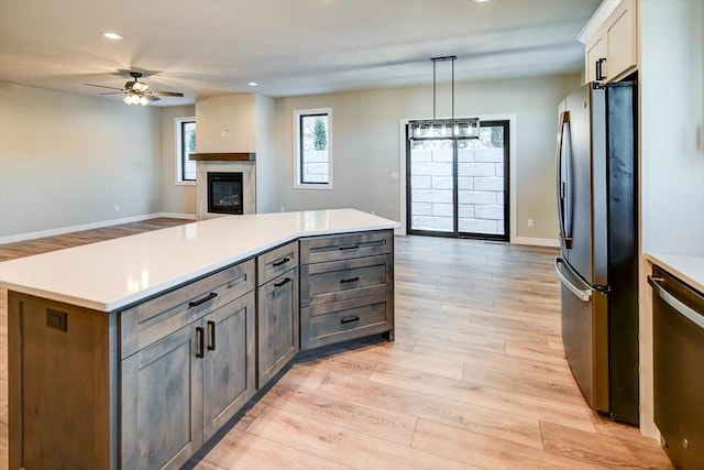 kitchen featuring light wood-style floors, open floor plan, light countertops, stainless steel dishwasher, and freestanding refrigerator