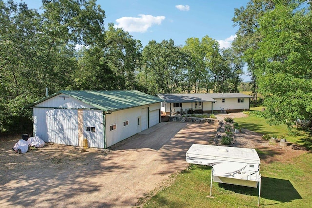 view of front of house featuring a garage, metal roof, an outdoor structure, and a front lawn