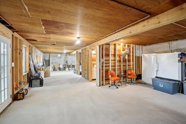 basement featuring wood ceiling, a wealth of natural light, and white fridge