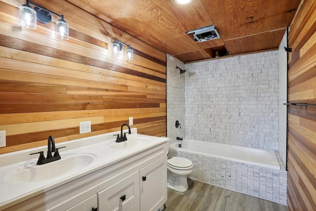 full bathroom featuring toilet, tiled shower / bath combo, wooden walls, and hardwood / wood-style flooring