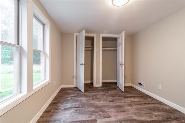 unfurnished bedroom featuring dark hardwood / wood-style flooring and multiple closets