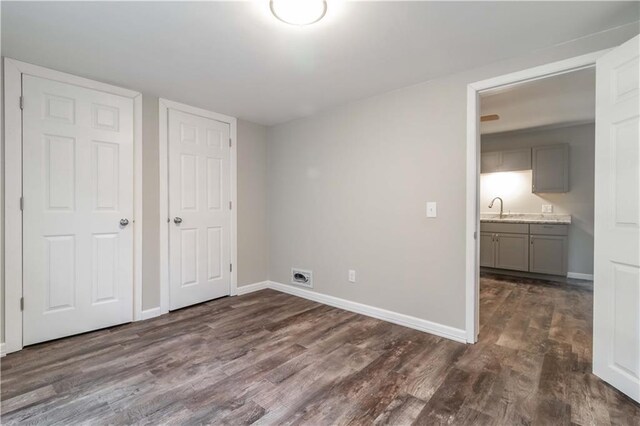 unfurnished bedroom with dark hardwood / wood-style flooring, connected bathroom, and sink