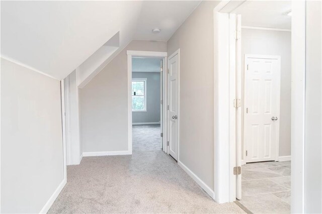 hall with lofted ceiling and light carpet