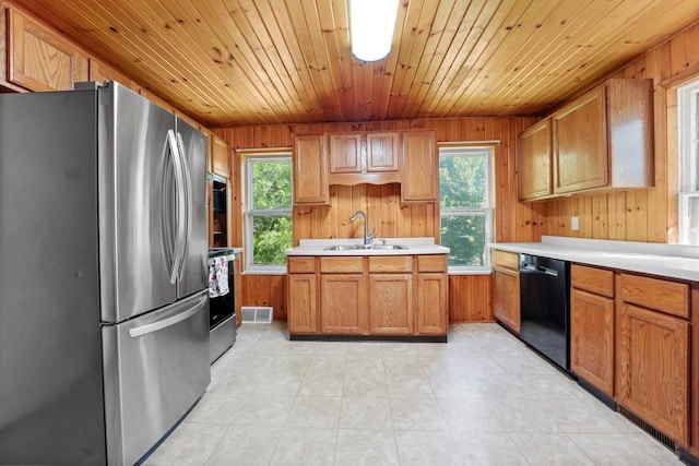 kitchen featuring wooden walls, appliances with stainless steel finishes, plenty of natural light, and sink