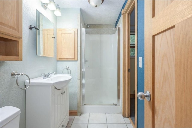 bathroom featuring a textured ceiling, vanity, walk in shower, tile patterned flooring, and toilet