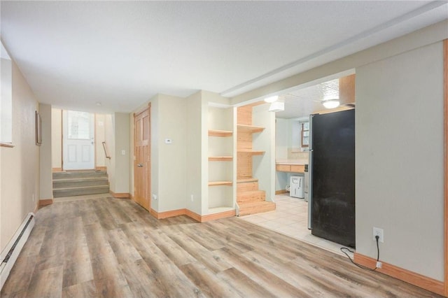 spare room featuring a baseboard heating unit and light hardwood / wood-style floors