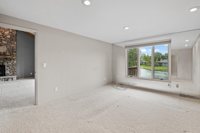 carpeted spare room featuring a fireplace