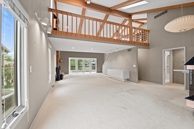 unfurnished living room featuring carpet flooring, high vaulted ceiling, and beam ceiling