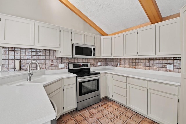 kitchen with vaulted ceiling, stainless steel appliances, white cabinetry, sink, and decorative backsplash