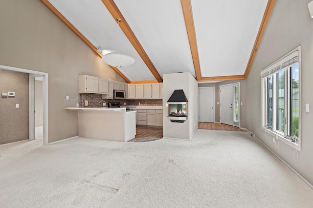 kitchen featuring light carpet, beamed ceiling, tasteful backsplash, stainless steel appliances, and white cabinets