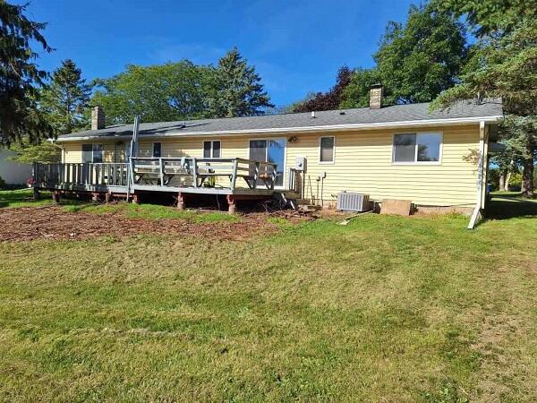 back of property featuring a wooden deck and a lawn