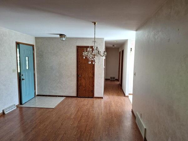 unfurnished room featuring a chandelier and light hardwood / wood-style floors