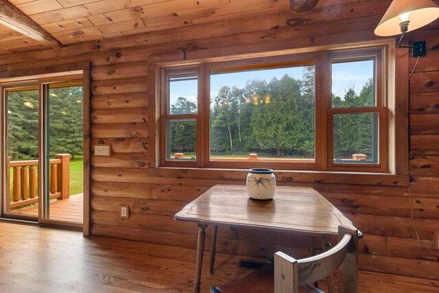 dining space featuring beamed ceiling, rustic walls, wood-type flooring, and wooden ceiling