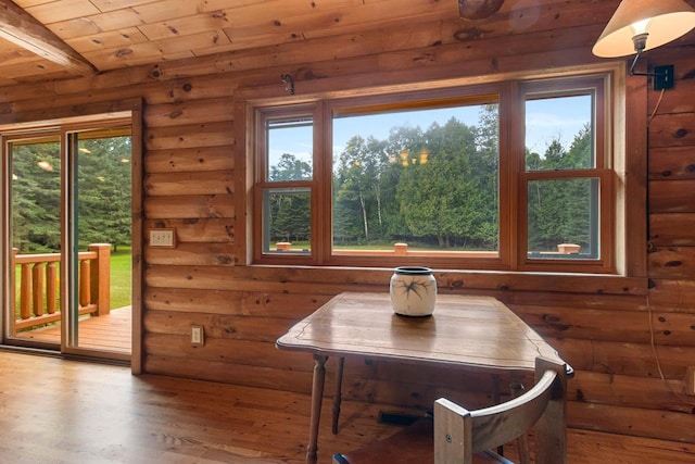 dining area featuring rustic walls, wood ceiling, a wealth of natural light, and wood finished floors