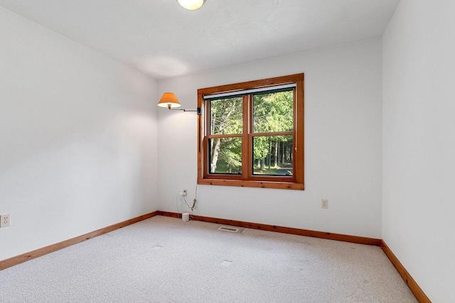 empty room featuring carpet floors, visible vents, and baseboards