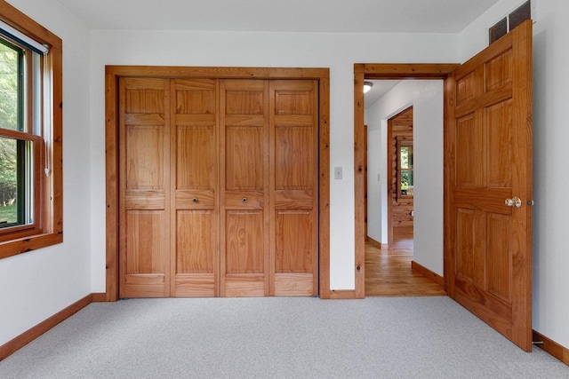 unfurnished bedroom with carpet floors, multiple windows, and baseboards