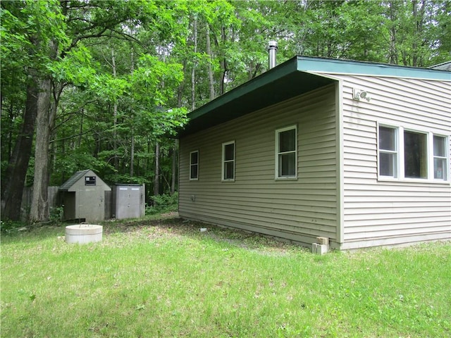 view of side of property with a storage shed and a lawn